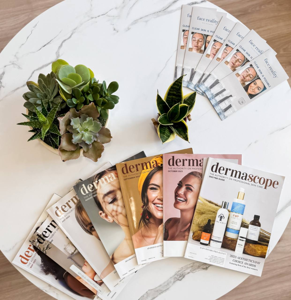 A display of facial care magazines and a small plant on a marble tabletop in Greenwich location.