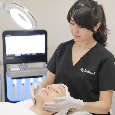 Aesthetician performs a facial treatment involving Hyndrofacial and buccal massage in Greenwich.